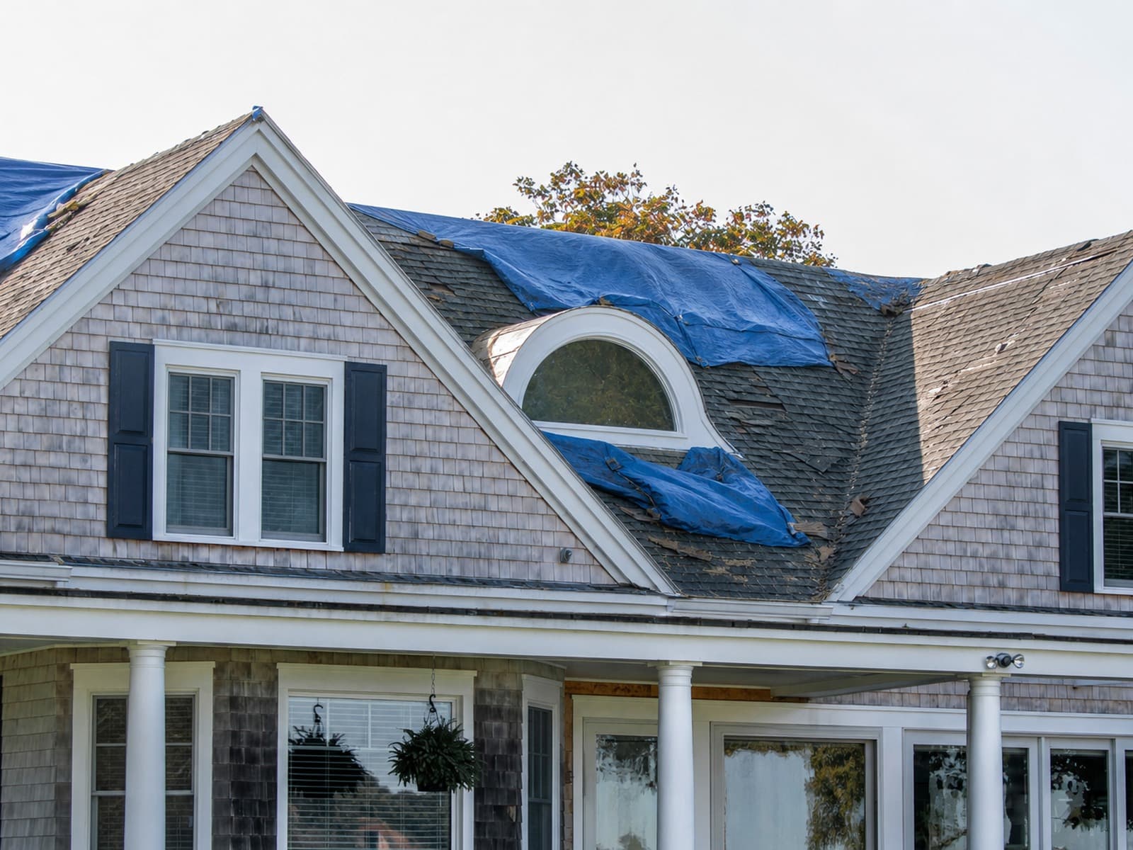 Same Cedar Park home after the storm — temporary blue tarps and missing shingles