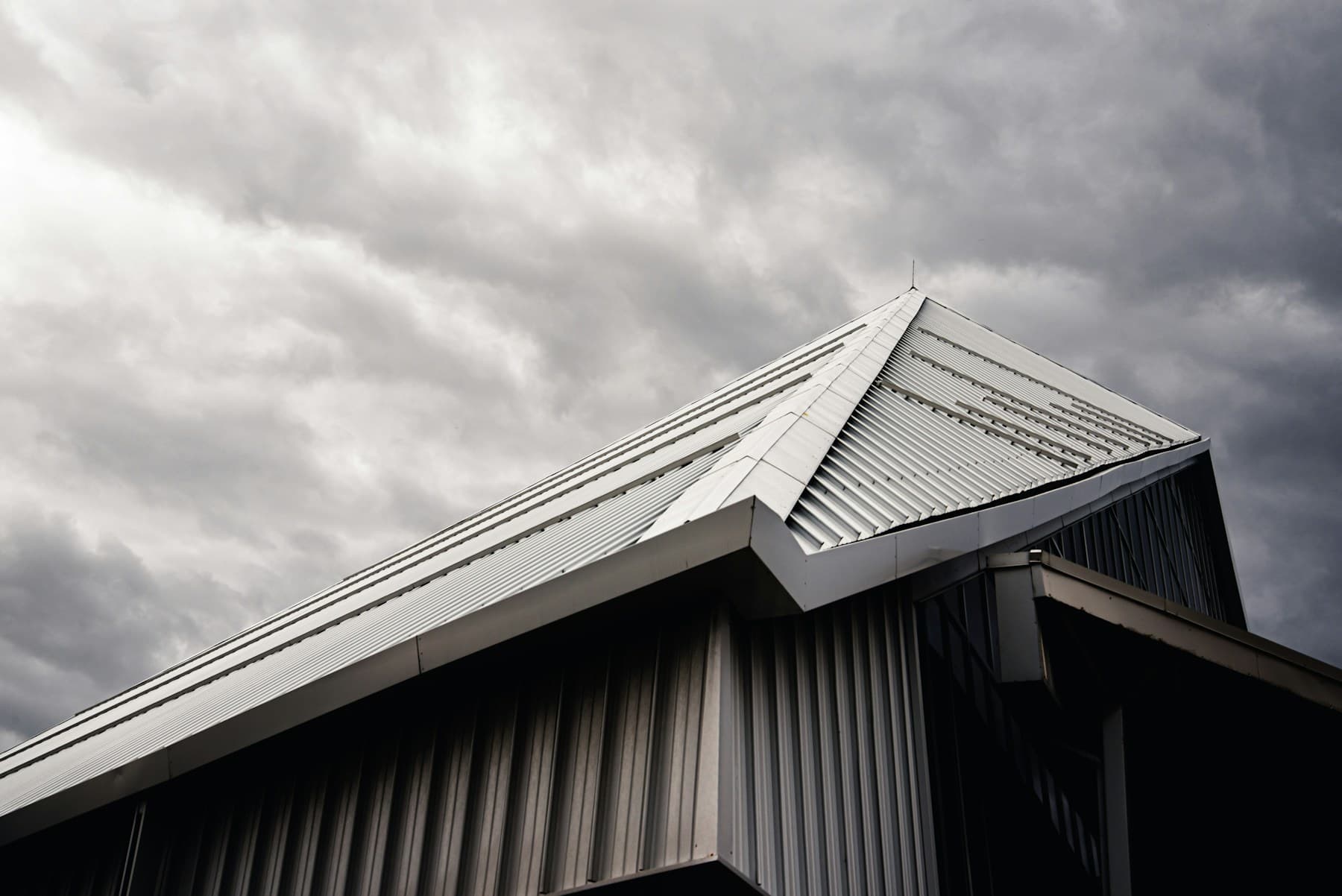 Angular standing seam metal roof against dramatic clouds