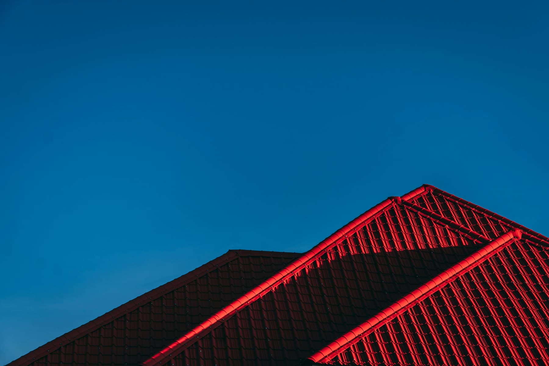 Red tile residential roof ridges against deep blue sky